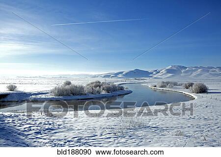 Stock Image - Snowy mountains and river in remote landscape. Fotosearch