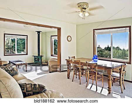 Stock Image - Sofa, dining table and wood stove in rustic open living space. Fotosearch