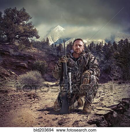 Picture - Soldier holding gun in dry rural landscape. Fotosearch
