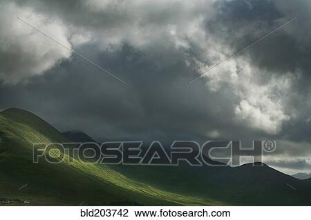 Stock Image - Sun break in clouds in rural landscape. Fotosearch