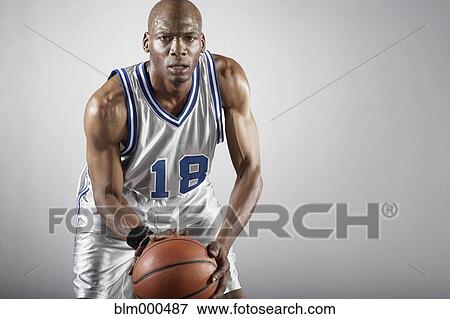 Stock Photo - Sweating Hispanic basketball player holding basketball. Fotosearch