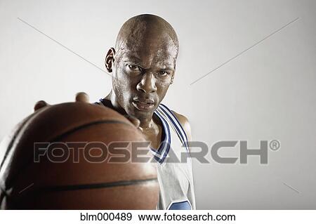 Stock Photo - Sweating Hispanic basketball player holding basketball. Fotosearch
