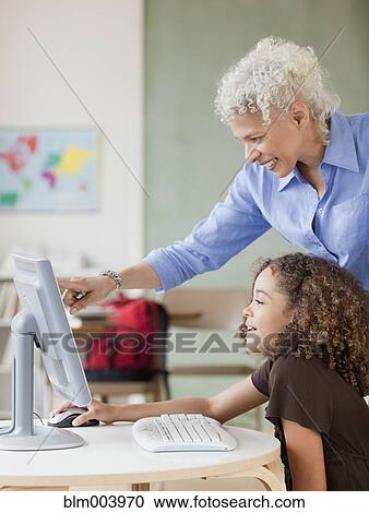 Stock Image - Teacher and student using computer. Fotosearch