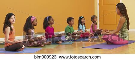Stock Image - Teacher leading class of children in exercise routine. Fotosearch