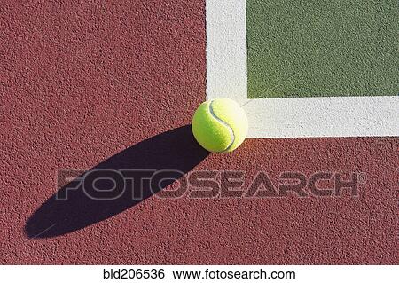 Stock Photograph - Tennis Ball Sitting on Edge of Tennis Court. Fotosearch
