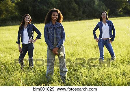 Stock Photo - Three women standing in meadow. Fotosearch