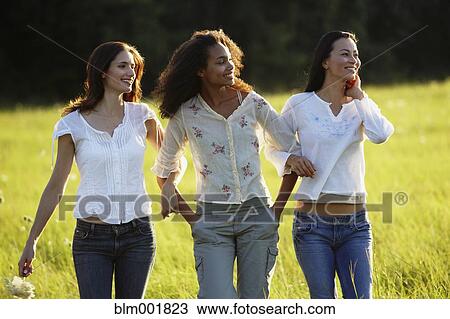 Stock Image - Three women walking through meadow. Fotosearch