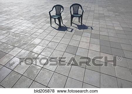 Stock Photo - Tiled patio space with two plastic garden chairs. Fotosearch