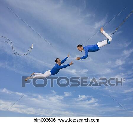 Trapeze artist watching partner fall View Large Photo Image Stock Photograph - Trapeze artist watching partner fall. Fotosearch