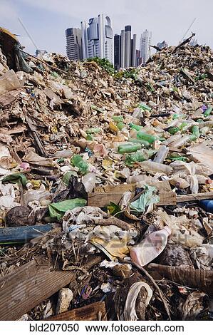Stock Image - Trash Mound with Modern Office Buildings Behind. Fotosearch