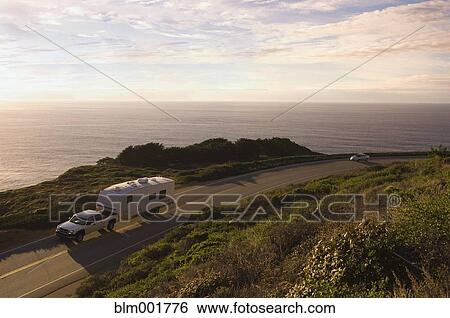 Stock Photograph - Truck pulling camper on coastal highway. Fotosearch