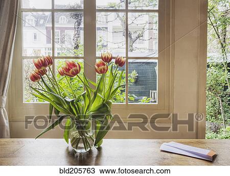 Stock Image - Tulips in vase on table by window. Fotosearch