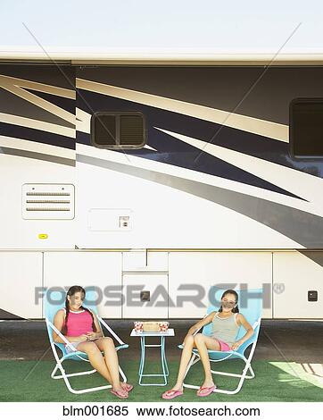 Two Hispanic sisters relaxing next to recreational vehicle View Large Photo Image Stock Photography - Two Hispanic sisters relaxing next to recreational vehicle. Fotosearch