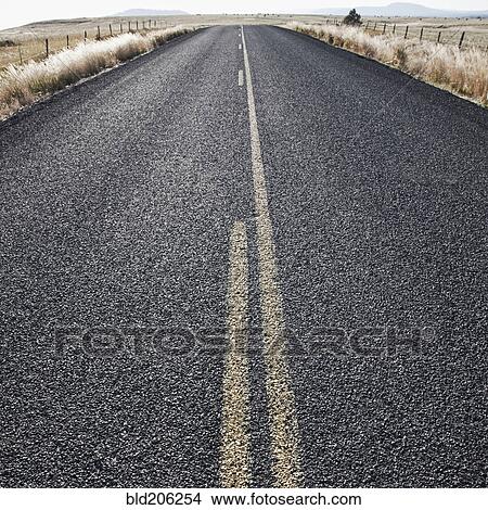 Picture - Two Lane Road Between Fenced Fields. Fotosearch