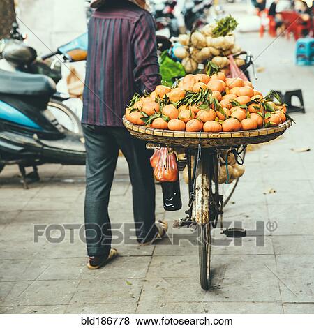 Stock Photo - Vendor pushing bicycle with fruit for sale. Fotosearch