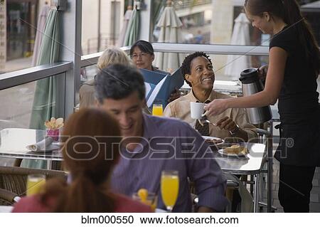 Stock Image - Waitress serving man coffee in restaurant. Fotosearch