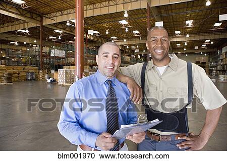 Stock Image - Warehouse worker and boss in warehouse. Fotosearch