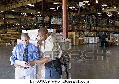 Stock Photo - Warehouse worker and boss next to pallet of boxes. Fotosearch