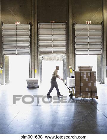 Stock Photo - Warehouse worker pushing pallet of boxes . Fotosearch