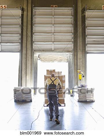 Stock Photo - Warehouse worker pushing pallet of boxes . Fotosearch