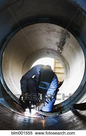 Stock Photography - Welder working inside large metal pipe. Fotosearch