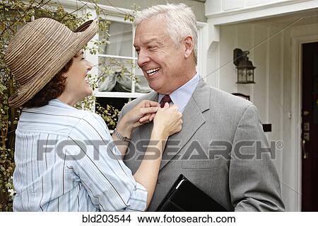 Woman adjusting husband's tie on front path View Large Photo Image Picture - Woman adjusting husband's tie on front path. Fotosearch