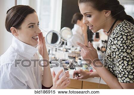 Stock Photography - Woman and makeup artist using cell phone. Fotosearch