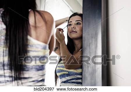 Woman applying makeup in mirror View Large Photo Image Stock Photo - Woman applying makeup in mirror. Fotosearch