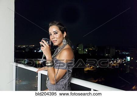 Stock Photography - Woman drinking wine on urban balcony. Fotosearch