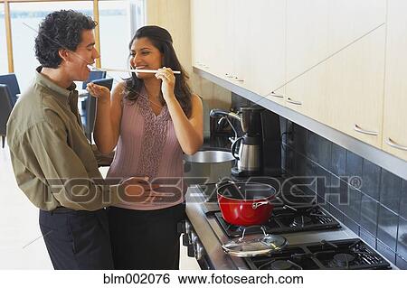 Stock Photograph - Woman feeding husband in kitchen. Fotosearch