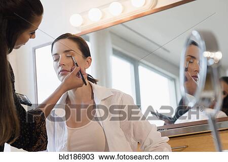 Stock Image - Woman having makeup applied by stylist. Fotosearch
