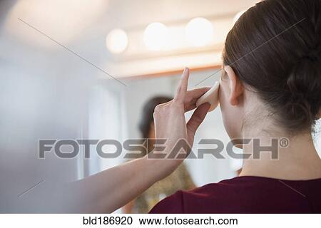 Stock Image - Woman having makeup applied by stylist. Fotosearch