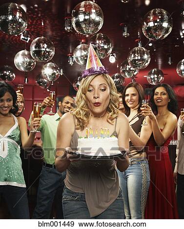 Woman in party hat blowing out candles on birthday cake View Large Photo Image Stock Photo - Woman in party hat blowing out candles on birthday cake. Fotosearch