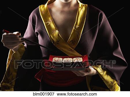 Woman in traditional Asian clothing eating sushi View Large Photo Image Stock Photo - Woman in traditional Asian clothing eating sushi. Fotosearch