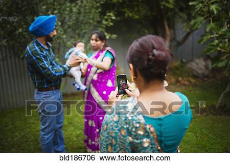 Stock Photograph - Woman photographing family with cell phone. Fotosearch