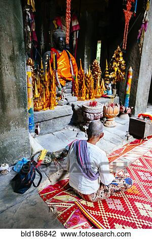 Stock Image - Woman sitting near Buddhist shrine. Fotosearch