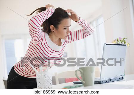 Stock Photo - Woman styling her hair with laptop. Fotosearch