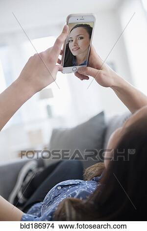 Woman taking selfie on sofa View Large Photo Image Picture - Woman taking selfie on sofa. Fotosearch