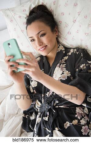 Woman using cell phone on bed View Large Photo Image Stock Photography - Woman using cell phone on bed. Fotosearch