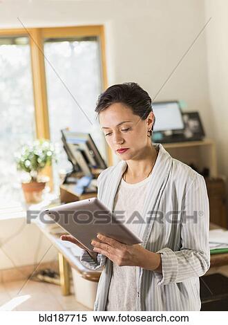 Woman using digital tablet in office View Large Photo Image Stock Photography - Woman using digital tablet in office. Fotosearch