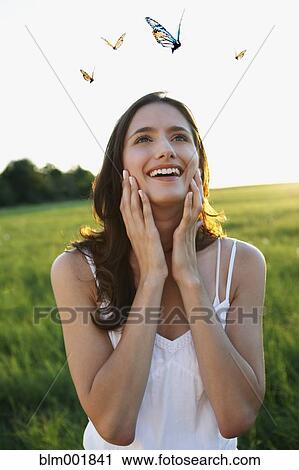 Stock Image - Woman watching butterflies in meadow. Fotosearch