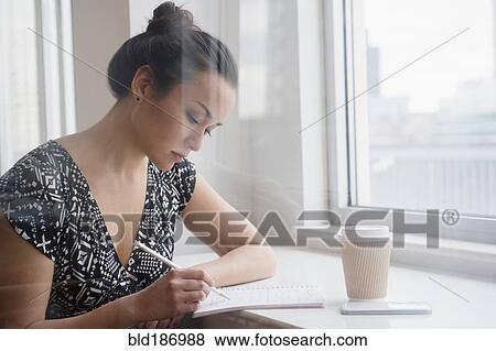 Stock Photo - Woman writing in coffee shop. Fotosearch