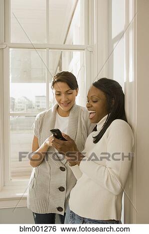 Stock Photograph - Women looking at cell phone. Fotosearch