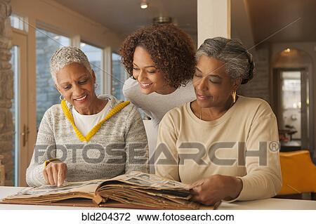 Women looking at family photo album View Large Photo Image Stock Image - Women looking at family photo album. Fotosearch
