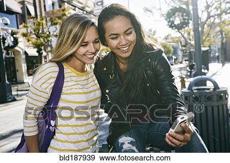 Women using cell phone outdoors View Large Photo Image Stock Photo - Women using cell phone outdoors. Fotosearch