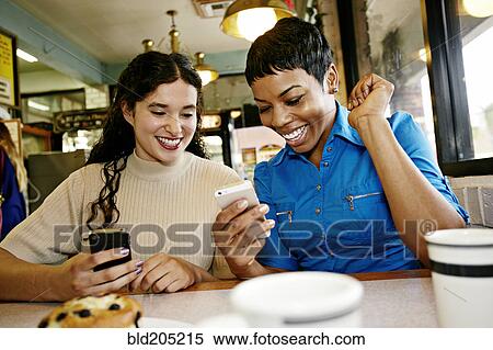 Stock Photography - Women using cell phones in restaurant. Fotosearch