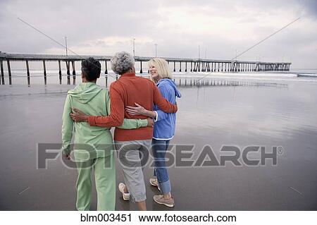 Stock Image - Women walking on beach together. Fotosearch