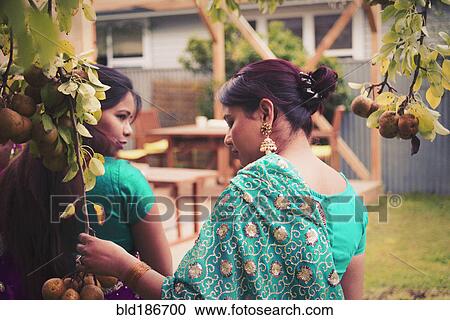 Stock Image - Women wearing Indian dresses in backyard. Fotosearch