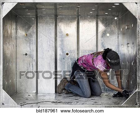 Stock Image - Worker examining metal walls. Fotosearch
