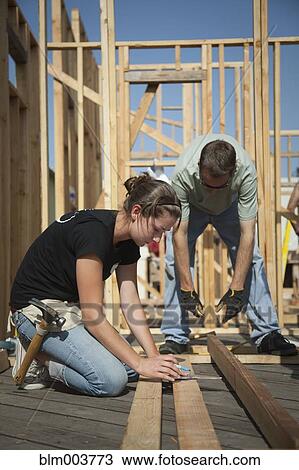 Workers measuring wood at construction site View Large Photo Image Stock Image - Workers measuring wood at construction site. Fotosearch